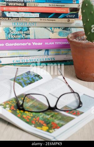Gardening books. UK. Gardeners glasses on a stack of her gardening books. Stock Photo