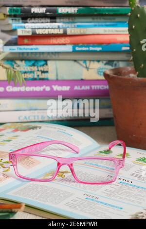 Gardening books. UK. Gardeners glasses on a stack of her gardening books. Stock Photo