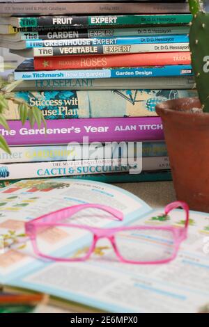 Gardening books. UK. Gardeners glasses on a stack of her gardening books. Stock Photo