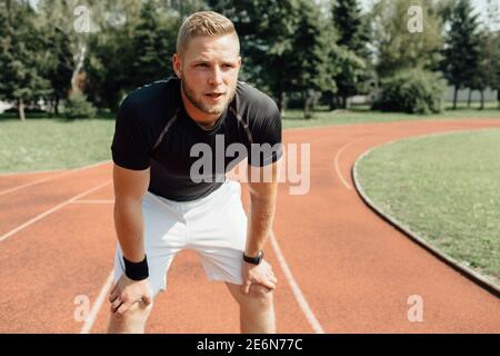 Close up of a male runner standing bent over and resting at a line Stock Photo