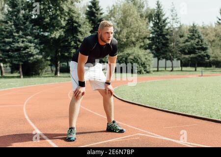 Exhausted runner standing bent over resting at a finish line Stock Photo