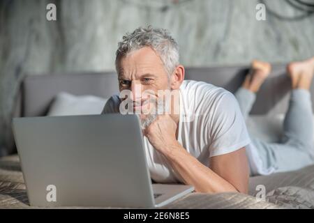 Smiling grey-haired man using a computer Stock Photo