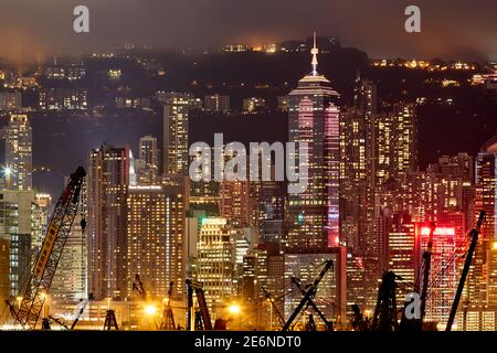 Hong Kong’s Central business district seen from Olympic in Tai Kok Tsui with the arms of cranes and crane barges in the foreground. Stock Photo