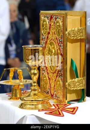 Holy Bible in golden cover, golden cup and candleholder placed on a table during church service Stock Photo