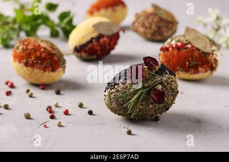 Eco-design of Easter eggs with various spices and cereals, without dyes and preservatives on a gray concrete background. Closeup Stock Photo