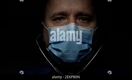 Doctor in a Hospital Wearing Protective Face Mask and Surgical Gloves Using a Stethoscope. Stock Photo