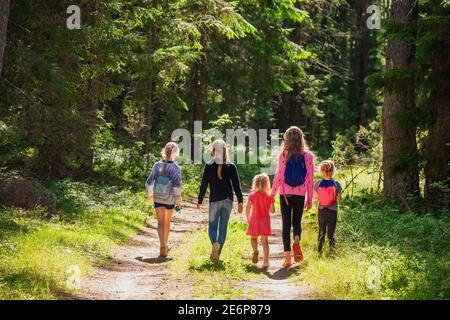 Little girls walking along a trail through summer forest enjoying warm sunny day- summer holidays concept Stock Photo