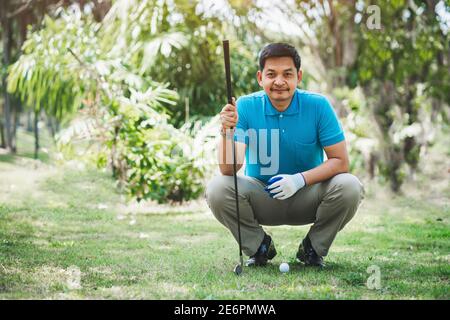 Golf player looking and sitting on field for playing golf on course tee Stock Photo