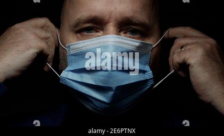 Doctor in a Hospital Wearing Protective Face Mask and Surgical Gloves Using a Stethoscope. Stock Photo