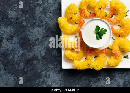 Close up view of fried shrimp with sauce on white plate over blue stone background with free text space. Top view, flat lay Stock Photo