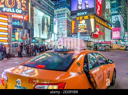 Passenger is Getting Out of a Yellow Taxi in Manhattan Times Square. Features Colorful Animated LED Screens and Billboards. New York City, USA Stock Photo