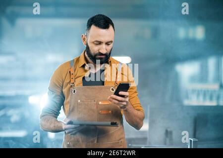 Factory worker with tablet and phone at the manufacturing Stock Photo