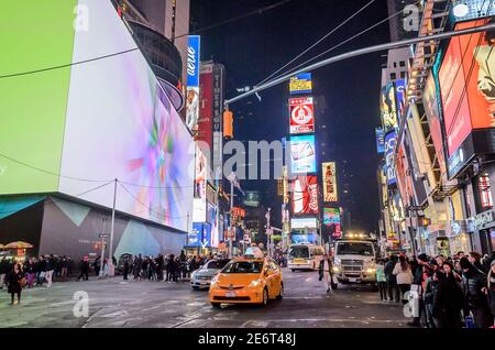 Vehicles Passing Through New York City Times Square. Big Animated LED Screens and Toshiba Tower in Background.  Manhattan, New York City, USA Stock Photo