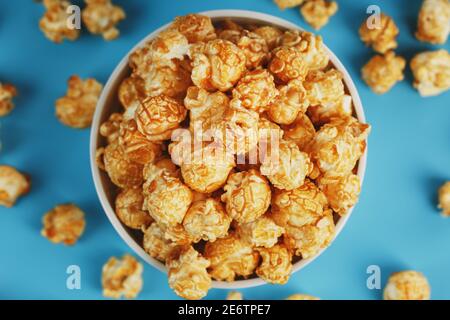 Caramel popcorn in a cup on a blue background, top view. Sweet fresh and flavorful dessert Stock Photo