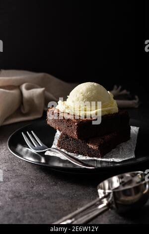 Brownie with vanilla ice cream scoop on black background Stock Photo