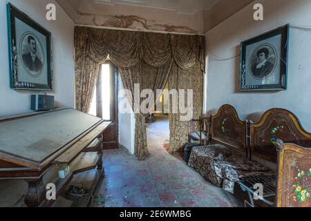 Room used as a study, furnished with vintage furniture, abandoned over time. Stock Photo