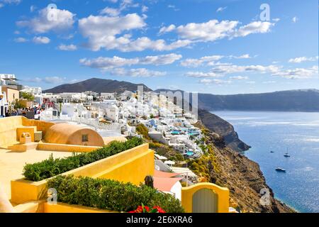 A scenic view of the Santorini caldera and the Aegean Sea from a resort terrace as tourists walk the main street in the hillside village of Oia Greece