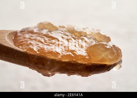 Cooled congealed beef bone broth on a wooden spoon against a white background Stock Photo