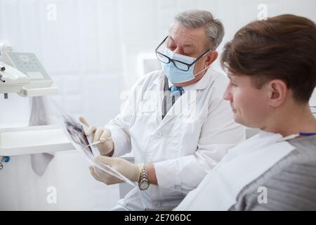 Male patient and his dentist looking at jaw x-ray scan on dental appointment Stock Photo