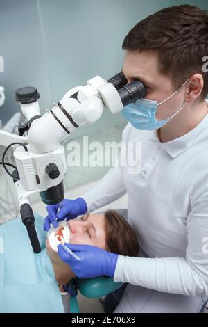 Vertical top view shot of a male dentist looking into dental microscope while working Stock Photo