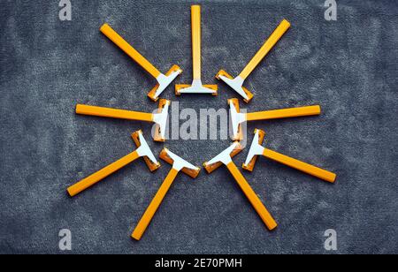 Many orange yellow razors in sun shape on gray background, shaving, hair removal disposable tools set Stock Photo