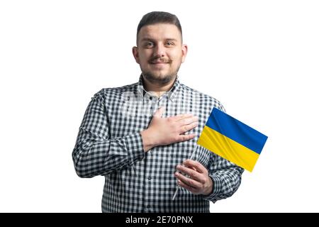 White guy holding a flag of Ukraine and holds his hand on his heart isolated on a white background With love to Ukraine. Stock Photo