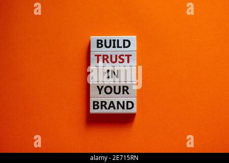Success business process symbol. Wood blocks stacking as step stair on orange background, copy space. Words 'build trust in your brand'. Business and Stock Photo