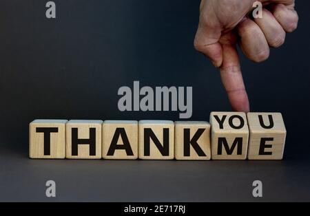 Thank you or me symbol. Businessman turns cubes and changes words 'thank me' to 'thank you'. Beautiful grey background, copy space. Business, psycholo Stock Photo