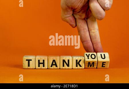 Thank you or me symbol. Businessman turns cubes and changes words 'thank me' to 'thank you'. Beautiful orange background, copy space. Business, psycho Stock Photo
