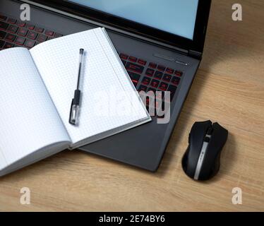 Laptop with wireless mouse, notebook and pen on the office table Stock Photo