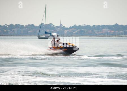 Two young guys on a jet ski are having fun in the Bassin d'Arcachon, Gironde, France. Guys are wearing live vests Stock Photo