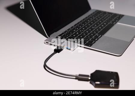 computer with peripheral device, picture is with intention strongly focused on the adapter, open laptop computer with usb-c to usb A,C, sd cart, micro Stock Photo
