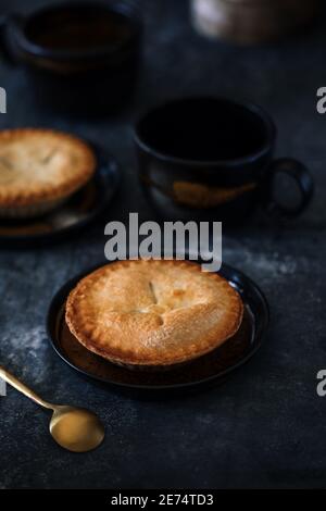 Three mini pies straight from the oven  on white wooden table with milk jug, cutting board Stock Photo