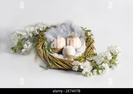 Design with gold painted eggs in the nest, on a white background, to celebrate easter Stock Photo