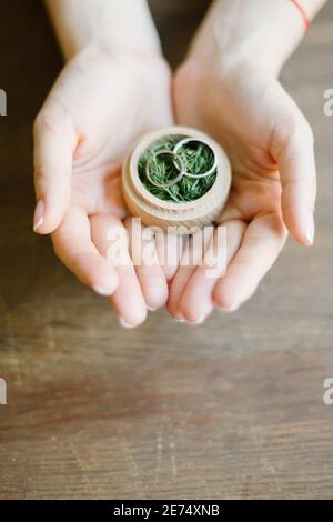 female hands holds wedding rings in a wooden box Stock Photo