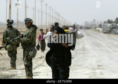 An Iraqi woman, a refugee from Baghdad, walks next to a U.S. Marine from Lima Company, a part of the 7th Marine Regiment, on the road south-east of the Iraqi capital April 5, 2003. U.S. Marine commander said on Saturday American troops would use overwhelming force to crush any resistance if ordered to storm Baghdad and that the battle would cost many civilian lives.   REUTERS/Oleg Popov   (IRAQ)