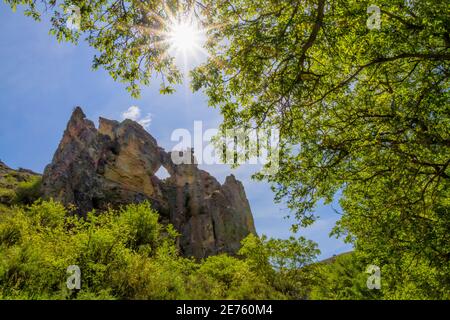 rocky mountain with a hole in the middle seen through some trees, in the Peregrina gorge en el Parque Natural del Rio Dulce, Guadalajara, Spain Stock Photo