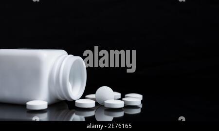 White pills and medicine bottles on black background. Stock Photo