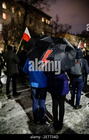 Kracow, Poland. 27th Jan, 2021. A couple is seen standing under an umbrella with the red lighting, a symbol of Women's Strike on it.After the Polish Constitutional Court verdict to implement one of the most restrictive anti-abortion laws in Europe came into effect on January 27th, hundreds of Poles took the streets in all major cities. Protests organized by the by the Women's Strike broke out again after the new anti-abortion bill was finally passed. Credit: SOPA Images Limited/Alamy Live News Stock Photo