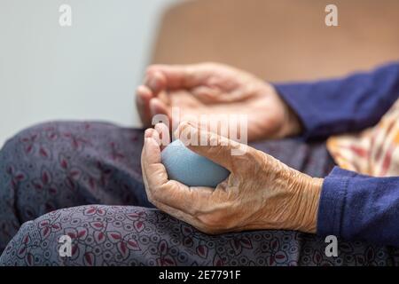 Elderly woman doing rubber ball for exercise fingers, palm ,hand and foot muscle with caregiver take care. Stock Photo