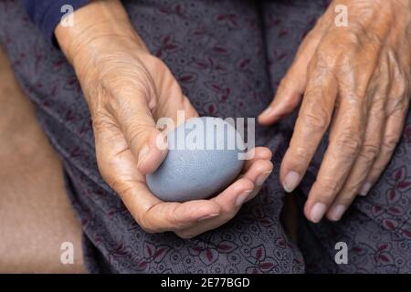 Elderly woman doing rubber ball for exercise fingers, palm ,hand and foot muscle with caregiver take care. Stock Photo