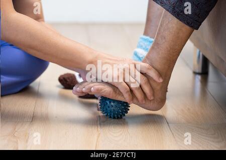 Elderly woman doing rubber ball for exercise fingers, palm ,hand and foot muscle with caregiver take care. Stock Photo