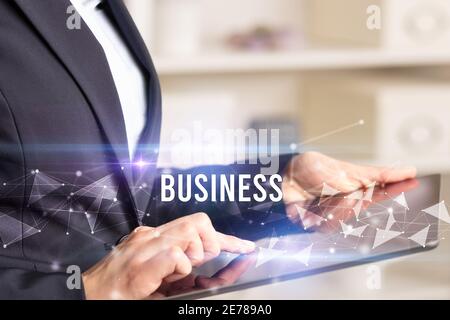 Close up hands using tablet with BUSINESS inscription, modern business technology concept