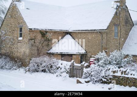 Cotswold stone cottage in Swinbrook in the snow. Swinbrook, Cotswolds, Oxfordshire, England Stock Photo