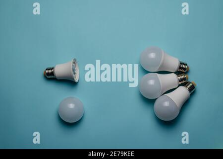 Creative minimalist composition with LED lights on a blue background. Three new bulbs are opposed to one bulb without a diffuser.  Flat Lay Stock Photo