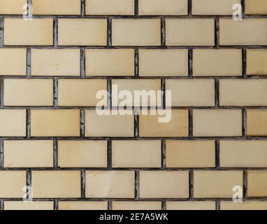 Light yellow colored, rectangular stone tiles, evenly spaced on a wall. Stock Photo