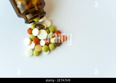 Medicine and pills. Multi-colored medicines on a white background close-up. Brown glass bottle with pills inside on a white background. Multi-colored Stock Photo