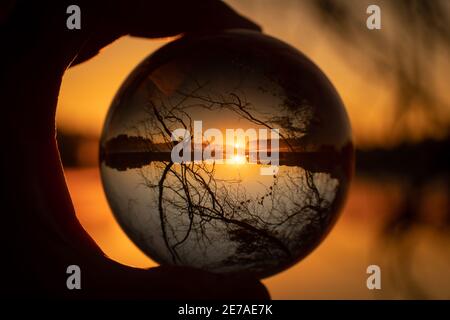 A beautiful golden sunrise over a lake as seen through a lensball. Stock Photo