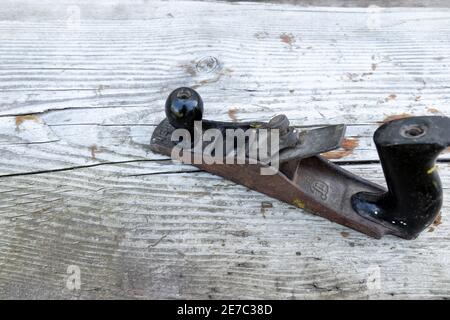 Old tool. A metal planer lies on a wooden table. Woodworking tool. Stock Photo