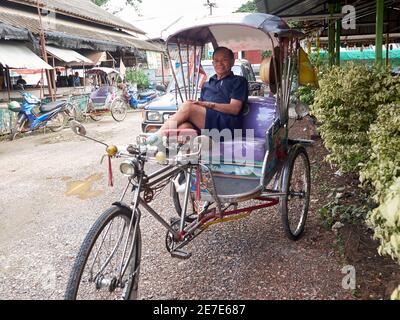 An old man pedicab driver, smiling posing while waiting for the arriving passengers Stock Photo